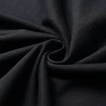 Tissu noir enroulé, texture douce et élégante, idéal pour la couture ou la décoration intérieure. Parfait pour des projets créatifs ou des vêtements sophistiqués.