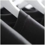 T-shirt noir en coton suspendu sur un cintre, vue rapprochée, fond flou.