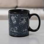 Mug en céramique noir avec illustrations des constellations du zodiaque : Gémeaux, Sagittaire, Lion, Bélier, et plus, avec noms en français.