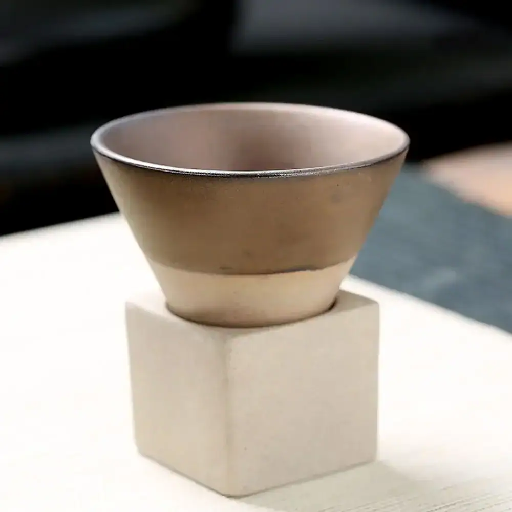 tasse-a-cafe-original-en-forme-de-cone-1 Petit pot en céramique beige posé sur un socle en béton blanc, idéal pour la décoration scientifique ou de bureau.