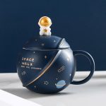 Vase en forme de planète avec un petit astronaute doré sur le couvercle, décoré d'étoiles et de planètes, parfait pour une décoration scientifique ou spatiale.
