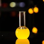 Vase de laboratoire en verre contenant un liquide jaune vif, utilisé pour des expériences scientifiques ou comme décoration d'inspiration scientifique.