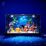 Vitrine d'aquarium scientifique avec décorations colorées, poissons en plastique et éléments marins, illuminée par une lumière bleue pour un effet captivant et éducatif.