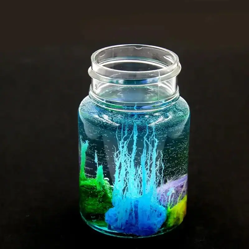 kit-jardin-chimique-1 Vase en verre contenant une expérience scientifique avec des liquides colorés et des bulles, illustrant un phénomène chimique ou physique captivant.