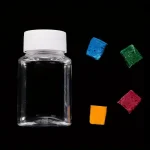 Bouteille en verre transparente avec un couvercle blanc, accompagnée de cubes de sucre colorés en bleu, vert, rouge et orange, sur fond noir.