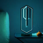 Clé LED moderne en forme de clé, éclairée d'une lumière bleue, posée sur une table avec une petite vase et un livre, décoratif et innovant pour un intérieur scientifique ou technologique.