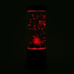 Bouteille de lave luminescente rouge dans l'obscurité, avec des bulles de gaz visibles à l'intérieur, créant un effet visuel captivant.