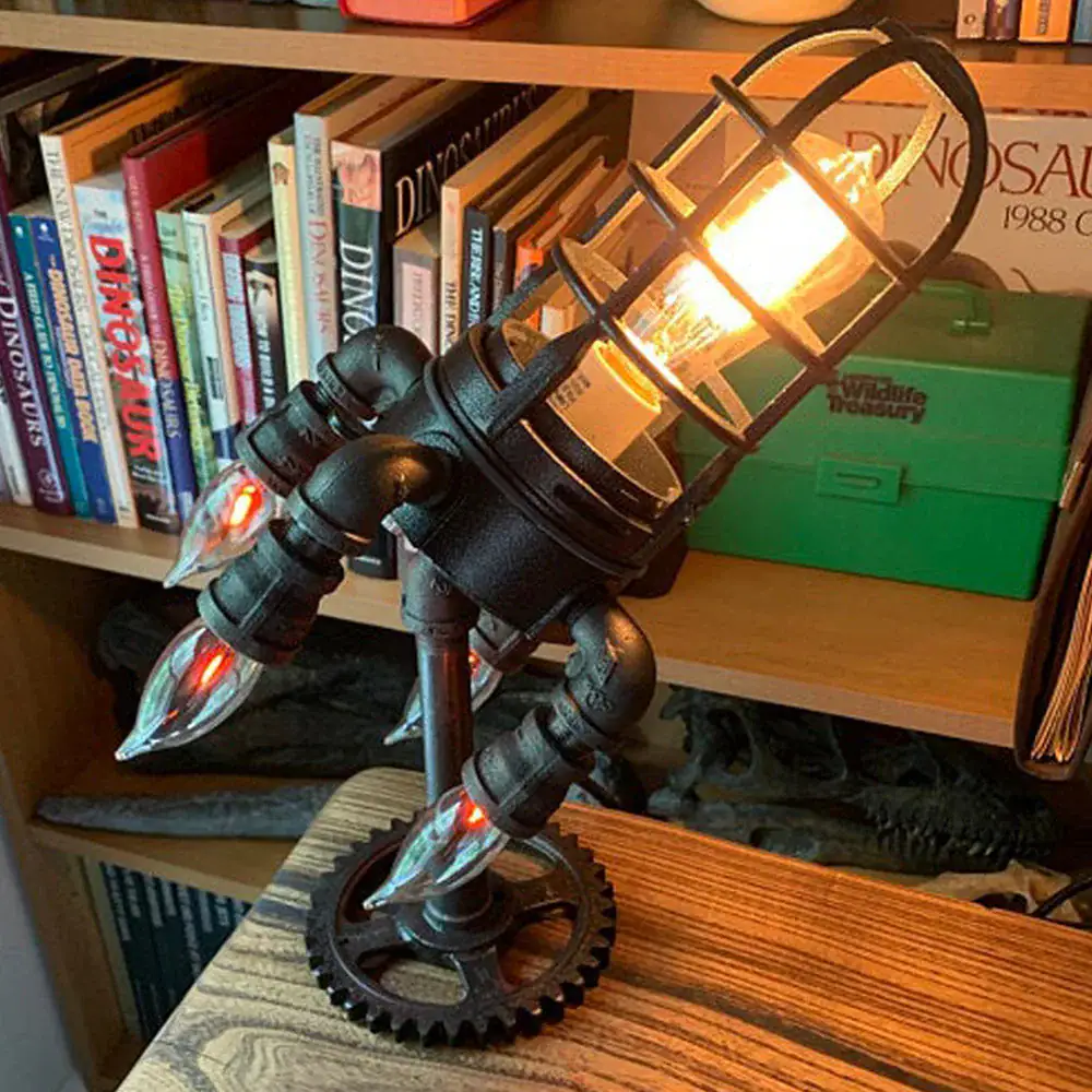 lampe-fusee-vintage-style-industriel-1 Lampe de bureau design inspirée d'une fusée avec éclairage chaud et structure métallique noire. Parfaite pour une décoration moderne ou thématique scientifique.