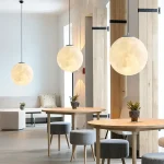 Suspension lumineuse en forme de lune, décoration intérieure moderne avec trois lampes suspendues rondes, ambiance chaleureuse et design épuré dans un espace contemporain.