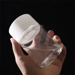 Verre à cocktail transparent avec couvercle en silicone blanc, tenu par une main, sur fond noir.
