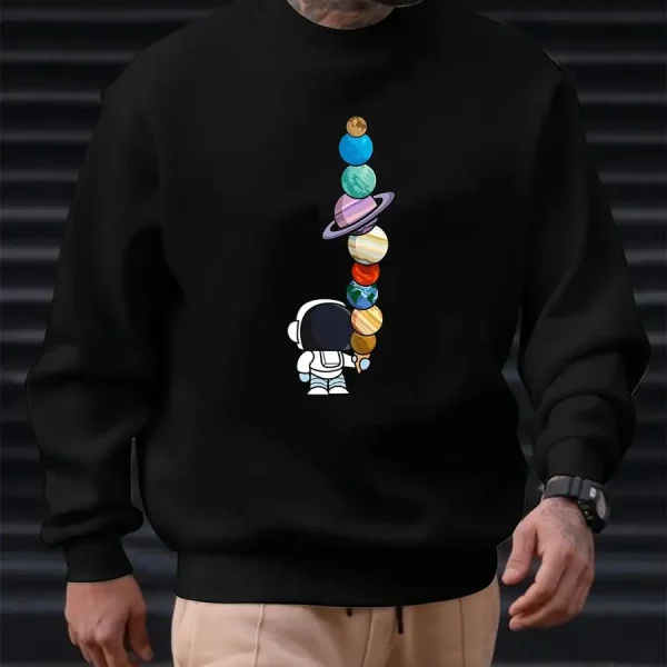 Sweatshirt noir avec motif de planètes colorées empilées et un petit astronaute, idéal pour les amateurs de science et d'astronomie. Confortable et tendance, parfait pour un look décontracté.
