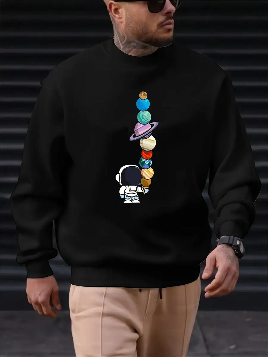 pull-astronaute-et-planete-1 Sweatshirt noir avec motif de planètes colorées empilées et un petit astronaute, idéal pour les amateurs de science et d'astronomie. Confortable et tendance, parfait pour un look décontracté.
