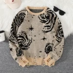 Pull en laine beige avec motifs de galaxies et étoiles noires, parfait pour un look cosy et original.
