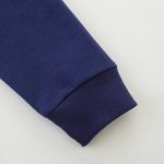 Manche de blouson en coton bleu marine avec poignets côtelés, vue rapprochée.