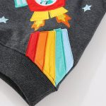 Vêtement pour enfant avec patch scientifique coloré, motif de fusée et étoiles, en tissu gris foncé, idéal pour une décoration ludique et éducative.