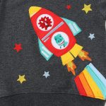 Vêtement pour enfant avec motif de fusée en patchwork coloré, étoiles et flammes, idéal pour une décoration ludique et scientifique.