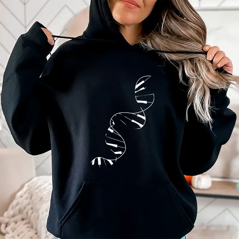 sweat-adn-piano-pour-femme-1 Une femme porte un sweat à capuche noir avec un motif de double hélice d'ADN blanc, illustrant la science et la génétique dans un style décontracté.