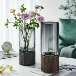 Vase en verre transparent avec socle en bois, idéal pour la décoration intérieure et la présentation de fleurs fraîches ou artificielles.