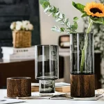 Vase en verre avec base en bois, idéal pour fleurs fraîches ou artificielles, apportant une touche naturelle et élégante à votre décoration.